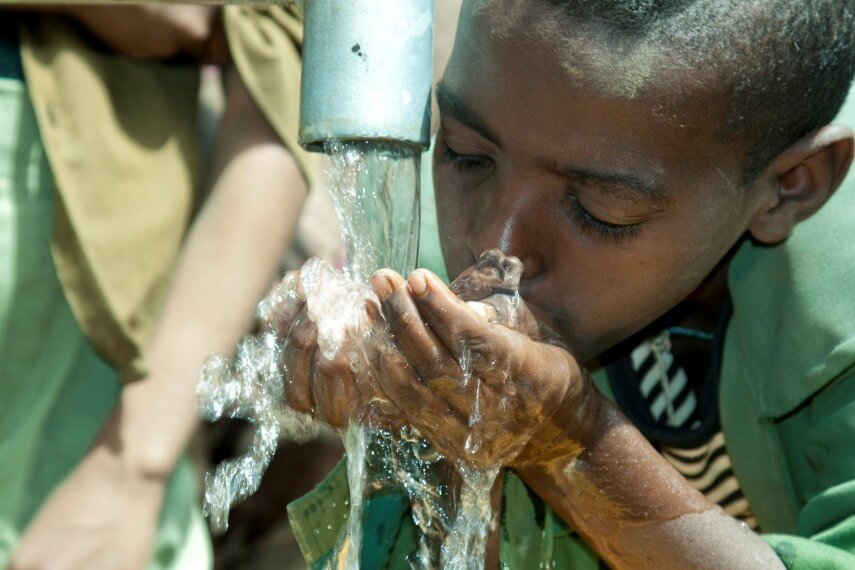 a kid drinking water from a water fountain